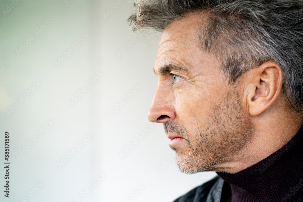 Close-up of serious thoughtful manager looking away against wall in office Close-up of serious thoughtful manager looking away against wall in office
