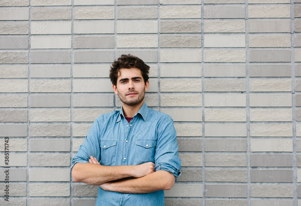 Handsome casual businessman with arms crossed standing against brick wall Handsome casual businessman with arms crossed standing against brick wall