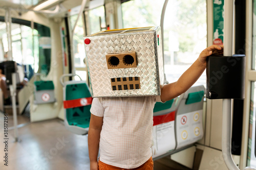 Boy wearing robot mask made of box standing in train