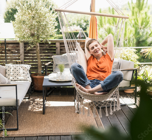 Mid adult woman with eyes closed relaxing on swing in porch photo