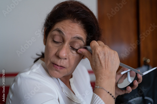 La señora se está arreglando las cejas con una cucharilla. photo