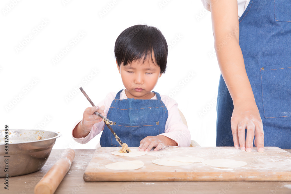 The little girl next to her mother earnestly learns to make dumplings The little girl next to her mother earnestly learns to make dumplings