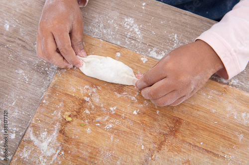 A pair of children's hands are learning to make dumplings
