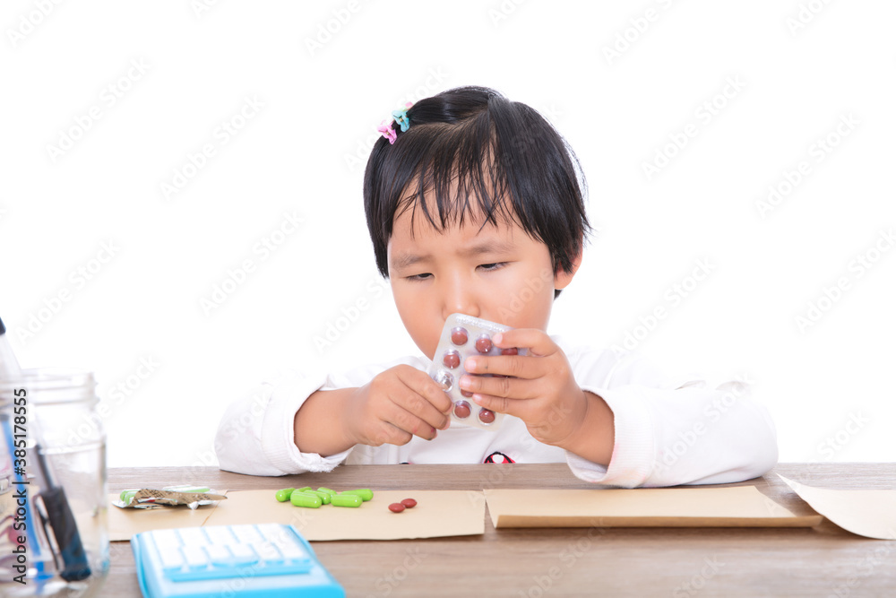 A little Chinese girl playing doctor dispensing medicine on the table in front of white background A little Chinese girl playing doctor dispensing medicine on the table in front of white background