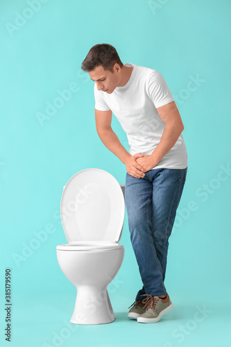 Man with problem of frequent urination on color background. Diabetes symptoms photo