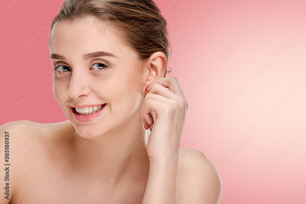 Beautiful smiling girl with clean fresh skin posing on pink background