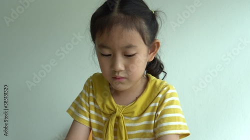 Cute smart primary school child girl learning writing doing math homework sit at home table, adorable pretty little preschool kid studying alone making notes, children elementary education concept