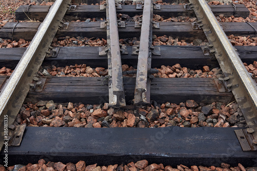 Oiled old steel rails and sleepers on rubble © dneezz