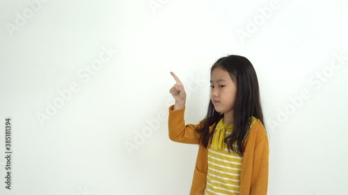 Adorable little girl pointing at wall. Isolated on white background
