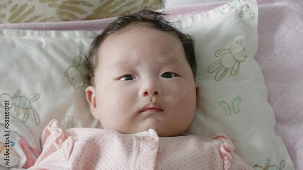 Close up shot of a 2 month old mixed asian baby lying in bed happily watching an electronic mobile rotate. Close up shot of a 2 month old mixed asian baby lying in bed happily watching an electronic mobile rotate.