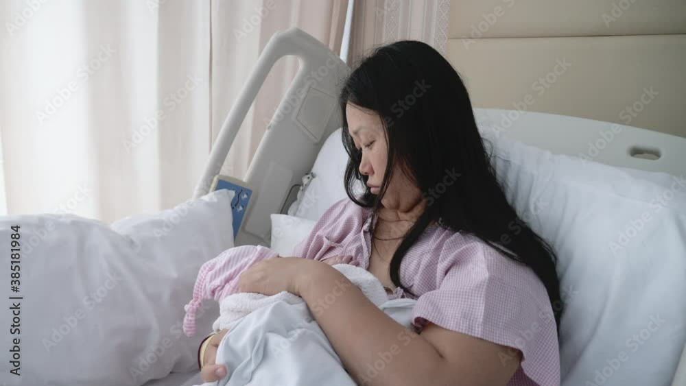 Medium shot of a tired Asian women breastfeeding her daughter. Medium shot of a tired Asian women breastfeeding her daughter.