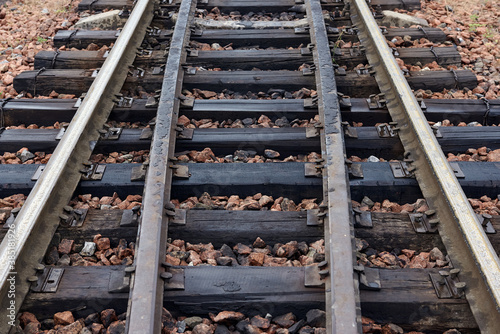 Oiled rusty steel rails and sleepers on rubble