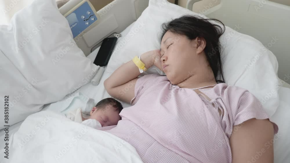 A new Asian mother and her child asleep in the hospital bed. A new Asian mother and her child asleep in the hospital bed.
