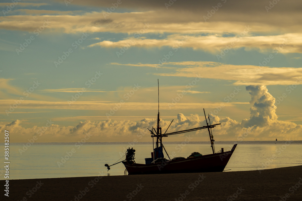 Silhouette of fishing vessel with beautiful sunrise on the beach and  cloud sky in the morning.