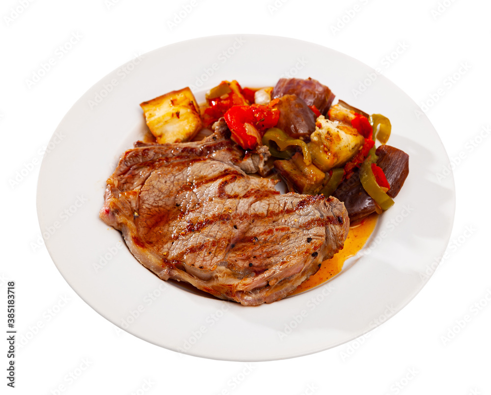 Delicious roasted veal steak with sauteed bell pepper, aubergine and onion. Isolated over white background