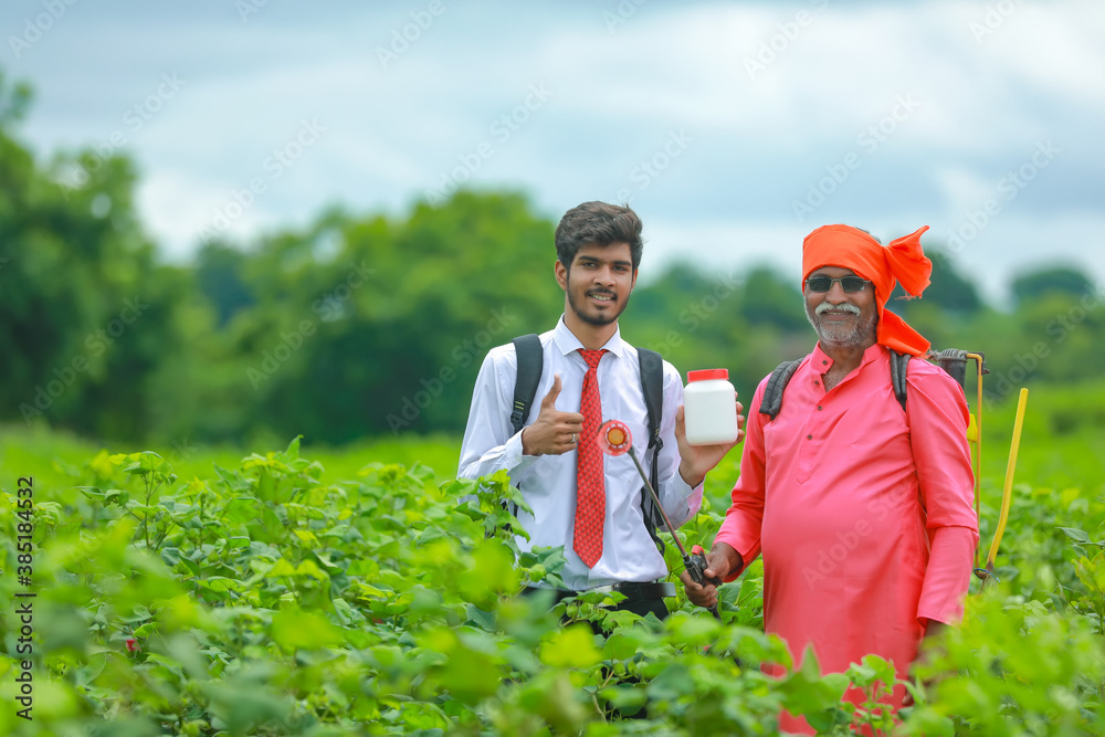 Young agronomist with farmer showing fertilizer botle in field Young agronomist with farmer showing fertilizer botle in field