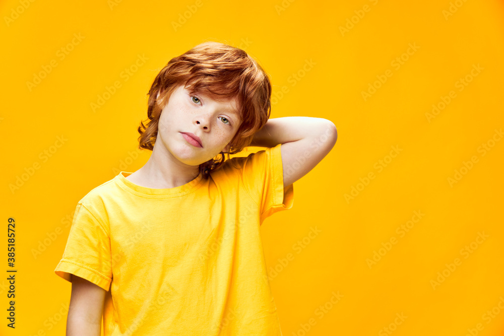 Cheerful red-haired boy front view yellow isolated background sad look 