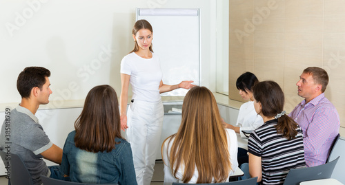 Woman reading out report to colleagues on meeting in office