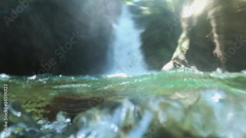 Underwater camera emerges near waterfall. Slow-motion photo