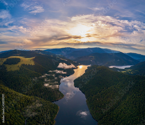 Aerial view clouds over the forest and lake at sunrise. View from drone. Aerial top view cloudscape. Transylvania, Romania 