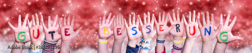 Children Hands Building Colorful German Word Gute Besserung Means Get Well. Red Snowy Christmas Winter Background With Snowflakes And Sparkling Lights