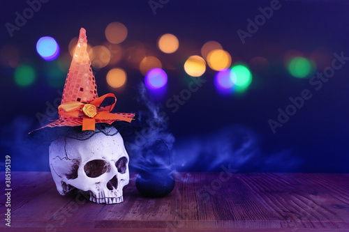 holidays halloween concept image. Pumpkin, witcher cauldron and skull over wooden table and black background