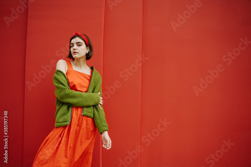 Posing beautiful young girl in red dress and green jacket. Dreaming hoping future in love mood. Expressive artistic conceptual composition. Banner poster size and style series of photos. Bob hair cut