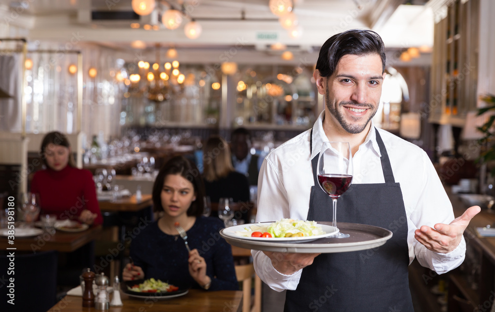 Handsome bearded waiter with serving tray welcoming to restaurant