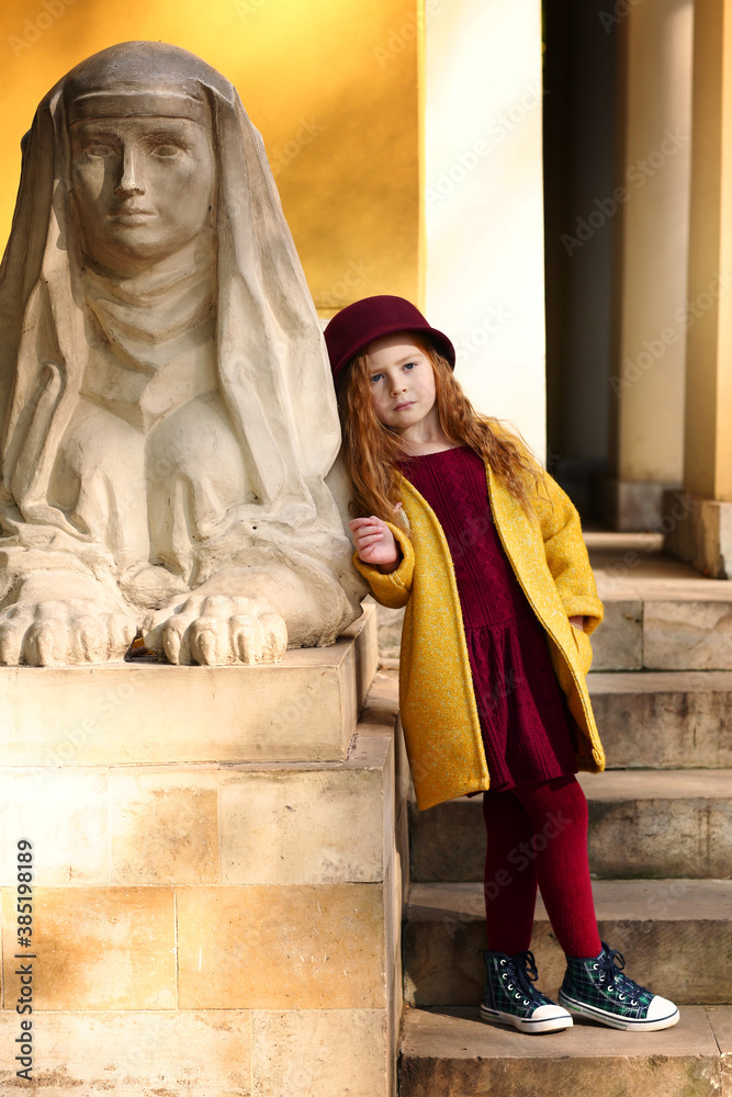 Irish little red haired girl outdoor photo on park architecture background