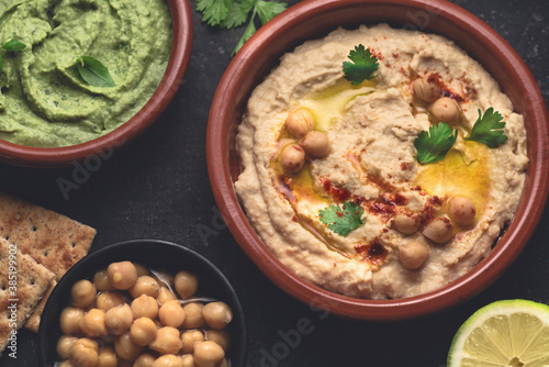 Various types of vegetarian hummus based on herbs, basil and coriander on a dark rustic background, close up. Healthy vegetarian food concept, vegetable proteins