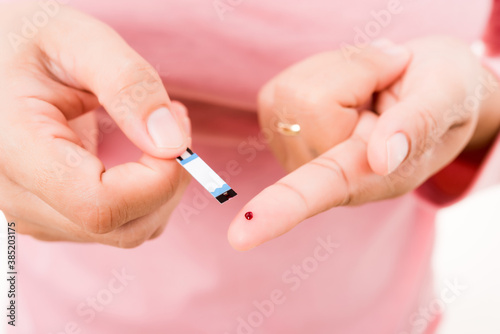 Closeup hands woman holding a plate measuring glucose test level checking with blood on a finger she monitors high blood sugar diabetes and glycemic health care concept isolated on white background