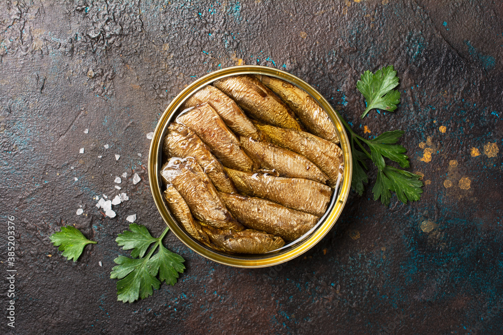 A can with golden sprats fish in oil with parsley