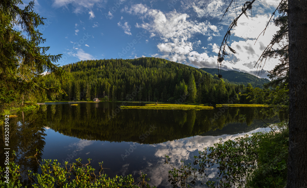reflection in a clear mountain lake with clouds on a blue sky panorama