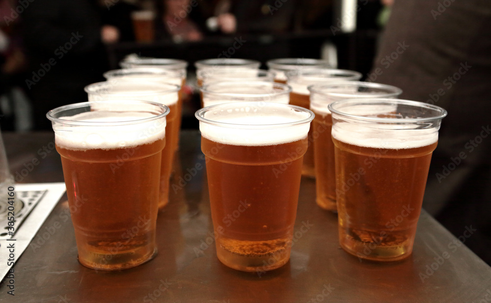 close up of three rows of beer in plastic glasses close up of three rows of beer in plastic glasses