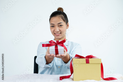 Asian woman holding a gift box Glad to be the giver of surprise with excitement, joy, and smiles on the holidays, Christmas, birthdays, or Valentine's Day concept