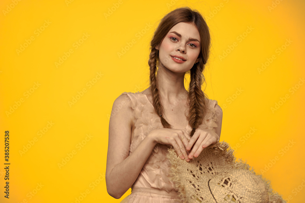 Woman in a straw hat in her hands on a yellow background emotions cropped view Woman in a straw hat in her hands on a yellow background emotions cropped view