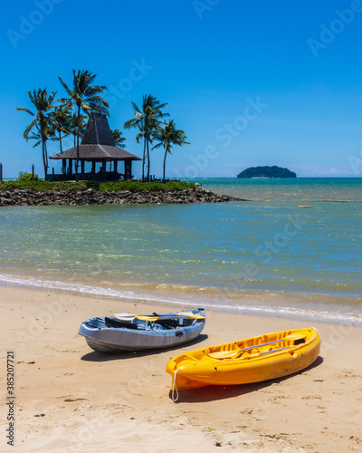 kayak boats at side Beach and palm trees over the clear blue sky In Kota Kinabalu Beach, Sabah, Malaysia