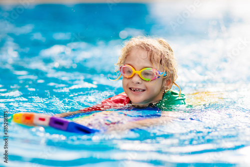 Child learning to swim. Kids in swimming pool.