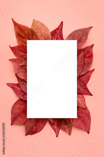 White mockup on red and orange autumn leaves on pink background vertical. Copy space.