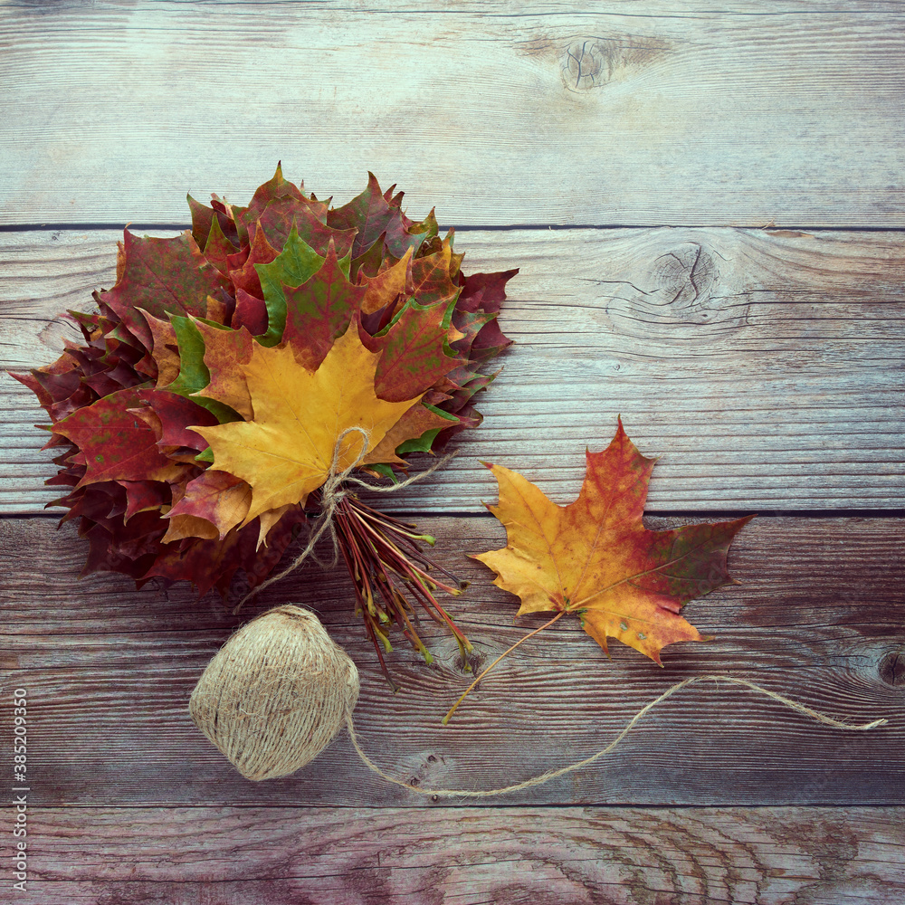 Obraz premium Bouquet or bunch made from colorful autumn leaves isolated on wooden background. Autumn, fall, thanksgiving day, nature concept. Flat lay, top view, copy space..