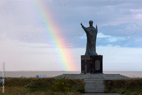 Picturesque view of the monument to St. Nicholas the Wonderworker and the beautiful rainbow over the Anadyr Estuary. Sights of the city of Anadyr and the Chukotka Autonomous Region. Far East of Russia