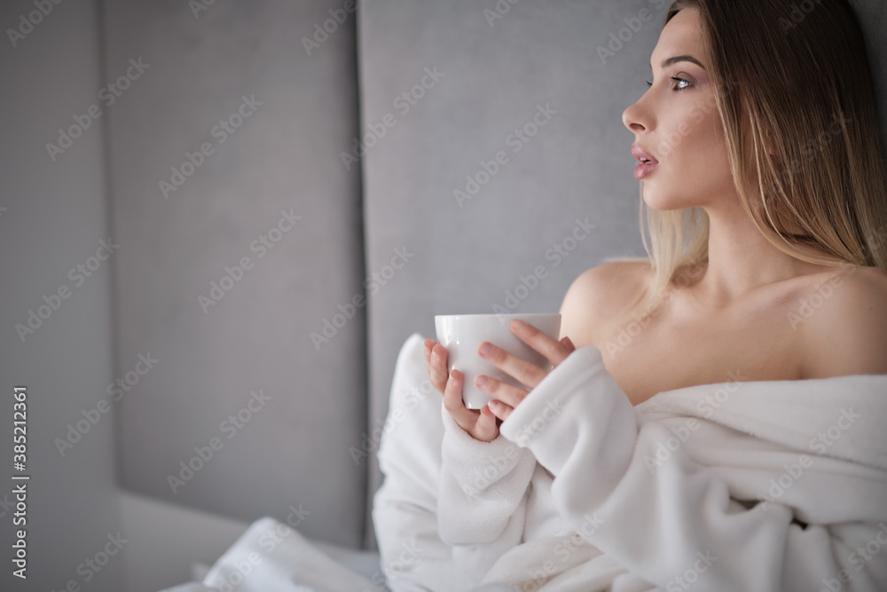 Beautiful Happy Young Woman Drinking Cup Of Coffee Or Tea While Lying In Bed After Waking Up In Morning. Closeup Portrait Of Smiling Girl Enjoying Her Drink While Relaxing At Home. Beautiful Happy Young Woman Drinking Cup Of Coffee Or Tea While Lying In Bed After Waking Up In Morning. Closeup Portrait Of Smiling Girl Enjoying Her Drink While Relaxing At Home.