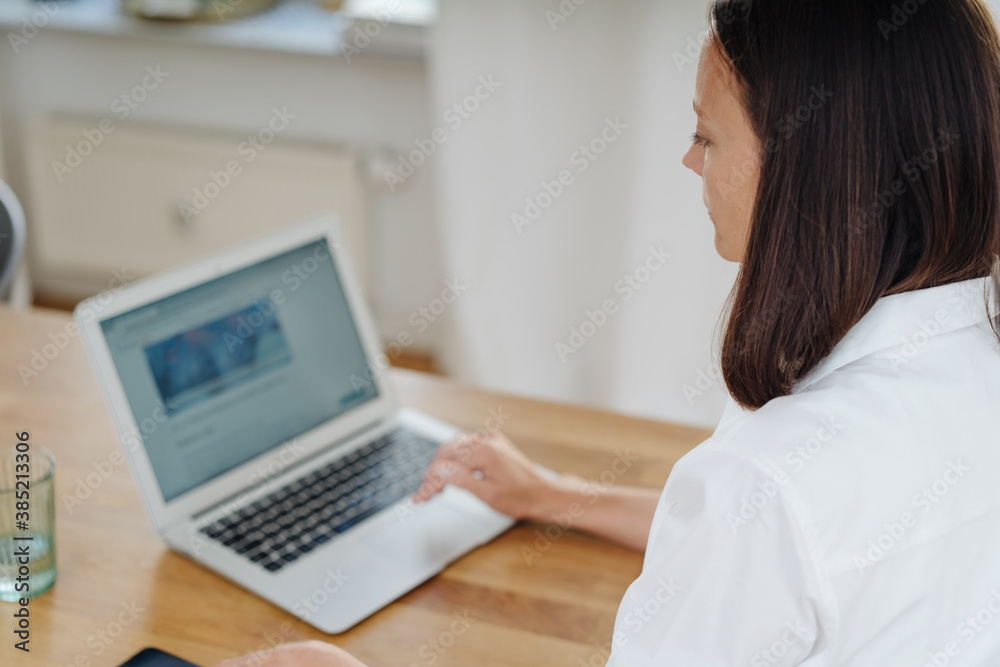 Over the shoulder view of woman using laptop Over the shoulder view of woman using laptop