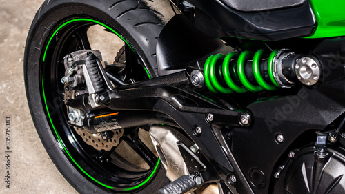 Rear of sports bike, wheel, engine, chassis and brake system, close-up. Fragment of green, beautiful motorcycle, shock absorber, cylinder, support. Sale of motorcycle in showroom in store. Banner