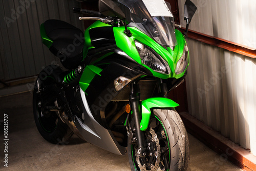 Sale of a used beautiful green sport bike with a price tag in the showroom in the store. Photo of a bright fast bike with full front windshield. Road bike in the garage after repair.