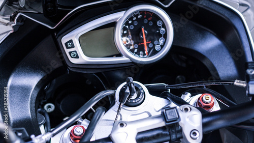 Steering wheel of sport bike. Modern electronic speedometer and pointer tachometer with indicators and keyhole, keys to motorcycle on handlebars close-up. Dashboard of road motorcycle, top view