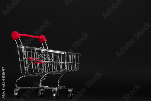 Shopping cart on a black background, a blank for the design, concept. Copy space.