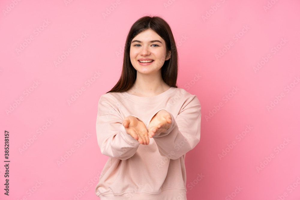 Young Ukrainian teenager girl over isolated pink background holding copyspace imaginary on the palm to insert an ad Young Ukrainian teenager girl over isolated pink background holding copyspace imaginary on the palm to insert an ad