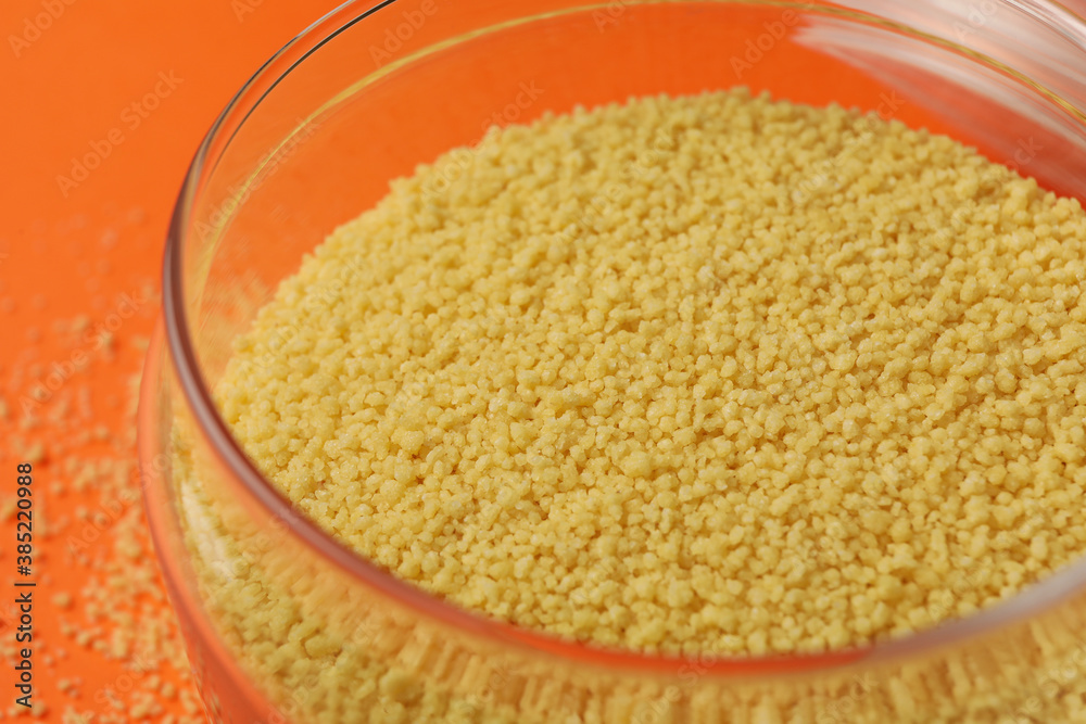 Glass jar with couscous on orange background Glass jar with couscous on orange background