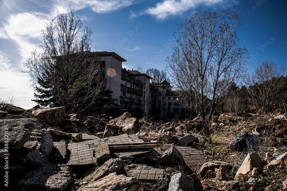 Antiguo sanatorio abandonado con arboles secos y escombros diversos